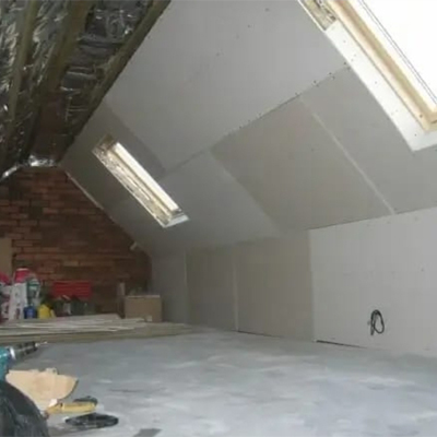 Loft room with exposed rafters and insulation, half covered with plasterboard